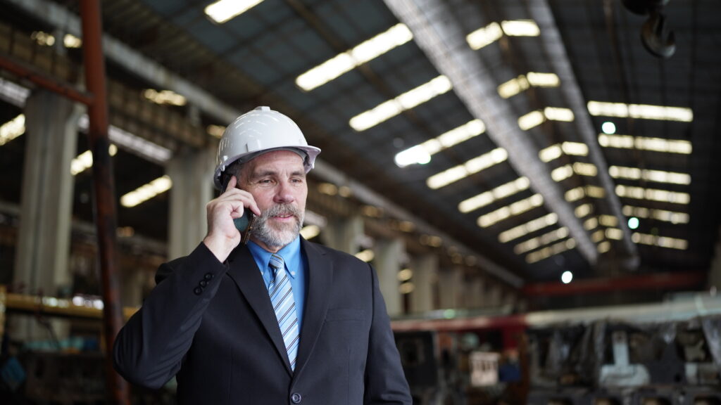 Factory manager or businessman in factory warehouse is talking on mobilephone.